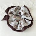 Détail d'un chouchou en mousseline fleurie avec bordure marron et pendentifs perles - Mousseline Double Couche Perle Café