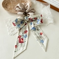 Detailansicht von Champagner-Seiden-Scrunchie mit Blumenband auf Vintage-Spitzenhintergrund - Khaki