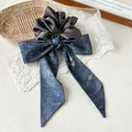 Detail eines grauen Satin-Haargummis mit dunkelblauem Blumenmuster-Schleifenband - Dunkelgrau