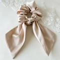 Detaillierte Textur eines eleganten champagnerfarbenen Satin-Scrunchie mit Schleife - Satin Khaki Band Haargummi
