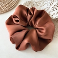 Gedetailleerde close-up van de donkere karamel satijnen scrunchie met zijdeachtige textuur - Karamel