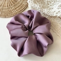 Close-up van lila satijnen scrunchie met een zijdeachtige glans en zachte elegante plooien - Paars