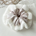 Détail d'un chouchou style ballet avec satin crème et couches de tissu plissé blanc - Champagne