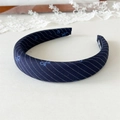 Close-up of blue fabric headband featuring white diagonal stripes and bow patterns - Dark Blue