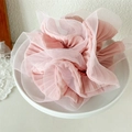 Close-up of pink layered organza scrunchie on ceramic dish with elegant ruffled details - Pink