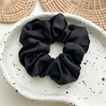 Close-up of black silk satin scrunchie on white tray with elegant pleated texture - Imitation Silk Black