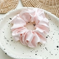 Detailed close-up of light pink satin scrunchie displayed on a ceramic dish - Imitation Silk Pink