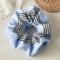 Détail d'un chouchou à rayures bleues sur sous-verre en bois avec décor dentelle - Fines Rayures Noires Bleu