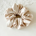 Gros plan sur un chouchou en satin champagne avec texture de soie lisse et plis doux - Beige