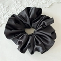 Detail of premium black satin scrunchie showing glossy texture and soft silk-like fabric folds - Black