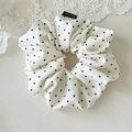 Detail eines cremefarbenen Satin-Scrunchies mit Herzmuster und Miniline-Webetikett - Schwarz Herz-Stil