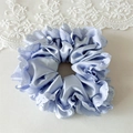 Detailed top view of a light blue satin scrunchie with white lace floral embroidery edges - Light Blue