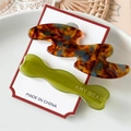Detalle de pinzas de acetato en carey y verde oliva en una tarjeta de presentación - Color de Esmalte Y Verde
