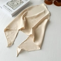 Detail of light beige silk scarf with smooth texture and soft luster on a white wood surface - Milky Yellow
