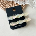 Detailed close-up of two iridescent white twisted acetate hair clips on display card - Mermaid White