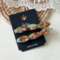 Close-up of twisted acetate hair clips in green and caramel marble texture on display - Jade Green