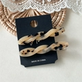 Close-up of two tortoise shell acetate twist hair clips on a display card with lace decor - Light Tortoiseshell