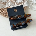 Detail of tortoiseshell acetate twist hair clips in blue and brown on lace background - Glazed Multi-color