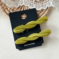 Detail of two twisted green acetate hair clips displayed on a black cardboard mount - Mustard Green