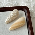 Close-up of two handmade acetate teardrop hair clips on a textured rustic background - Beige Apricot