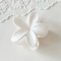 Vue détaillée d'une pince à cheveux en résine brillante en forme de fleur de frangipanier - Fleur Blanche