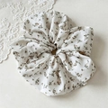 Detail eines großen Blumen-Scrunchies mit braunen Blüten auf hellem Chiffon-Stoff - Gebrochenes Weiß