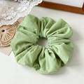 Close-up of light green oversized pleated hair scrunchie with soft fabric texture - Green