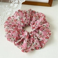 Détail d'un chouchou en mousseline avec motifs roses rouges et paillettes dorées - Rose