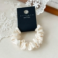 Elegante elastico scrunchie in raso crema effetto seta con morbide pieghe su carta - Bianco Sporco