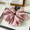 Close-up of a handmade light pink satin scrunchie with high elasticity and elegant shine - Pink