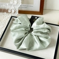 Detail of light green satin scrunchie with handmade card on elegant display tray - Green
