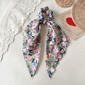 Makro-Detail von Blumen-Seidenhaarband mit langen Bändern auf einem Spitzenhintergrund - Streamer-Stil / Blau