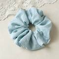 Detailaufnahme eines blau-weißen Gingham-Stoff-Haargummis mit feiner Nähtechnik - Blaues Karo Haargummi