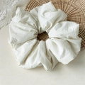 Dettaglio di uno scrunchie in spugna bianco crema con trama a pieghe naturali e dettagli tessuto - Bianco Sporco