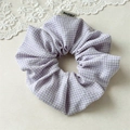 Dettaglio dello scrunchie a quadretti viola con etichetta tessuta su sfondo chiaro - Elastico a quadretti viola