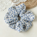 Détail d'un chouchou en mousseline à fleurs bleues sur fond de dentelle et de rotin tressé - Petit Floral Bleu