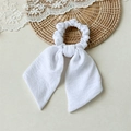 Detail of a white bow hair scrunchie with long ribbons on a natural woven mat - Solid White