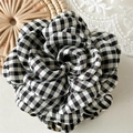 Dettaglio della pinza per capelli camelia in tessuto a scacchi bianco e nero con petali a strati - Nero
