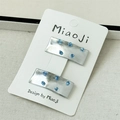Vue détaillée de deux barrettes rectangulaires argentées avec perles bleues sur carte - Zircon Bleu