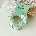 Dettaglio dell'elastico per capelli in cotone bianco con cuciture verdi e etichetta HenJu - Verde