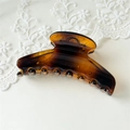 Macro detail of amber tortoiseshell hair claw clip with glossy resin finish on lace background - Large Coffee