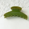 Close-up of translucent olive green hair claw clip with a glossy finish and metal spring - L Green