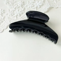 Detail of elegant glossy black fan-shaped hair claw clip on a soft floral lace background - L Black