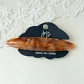 Detail of an amber marble acetate hair clip with Amy bear engraving on black card - Brown