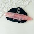 Detailed macro view of pink acetate hair clip with marble texture on logo display card - Pink