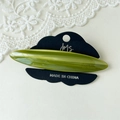 Detailed macro view of olive green marble pattern acetate hair clip on display card - Green