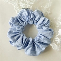 Détail d'un chouchou en tissu à carreaux bleus avec strass scintillants et étiquette tissée - Bleu