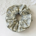 Nahaufnahme des Oversize-Haargummis mit floralem Muster und blauen Drucken auf Beigestoff - Großer Scrunchie mit Blumenmuster