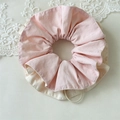 Detailopname van tweekleurige geel en beige scrunchie met zachte katoenen textuur - Roze