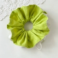 Detailweergave van een grote groen-witte scrunchie met zachte stof en ruches - Groen